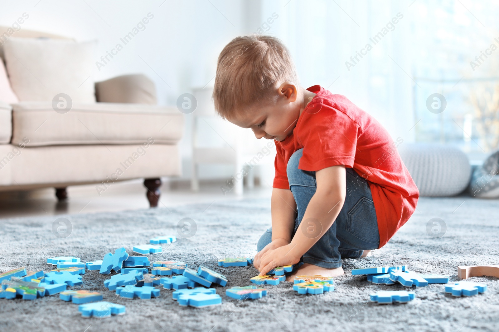 Photo of Cute little child playing with puzzles on floor indoors