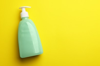 Photo of Bottle of liquid soap on yellow background, top view. Space for text