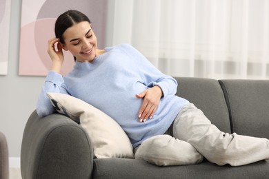 Photo of Happy pregnant woman on sofa at home