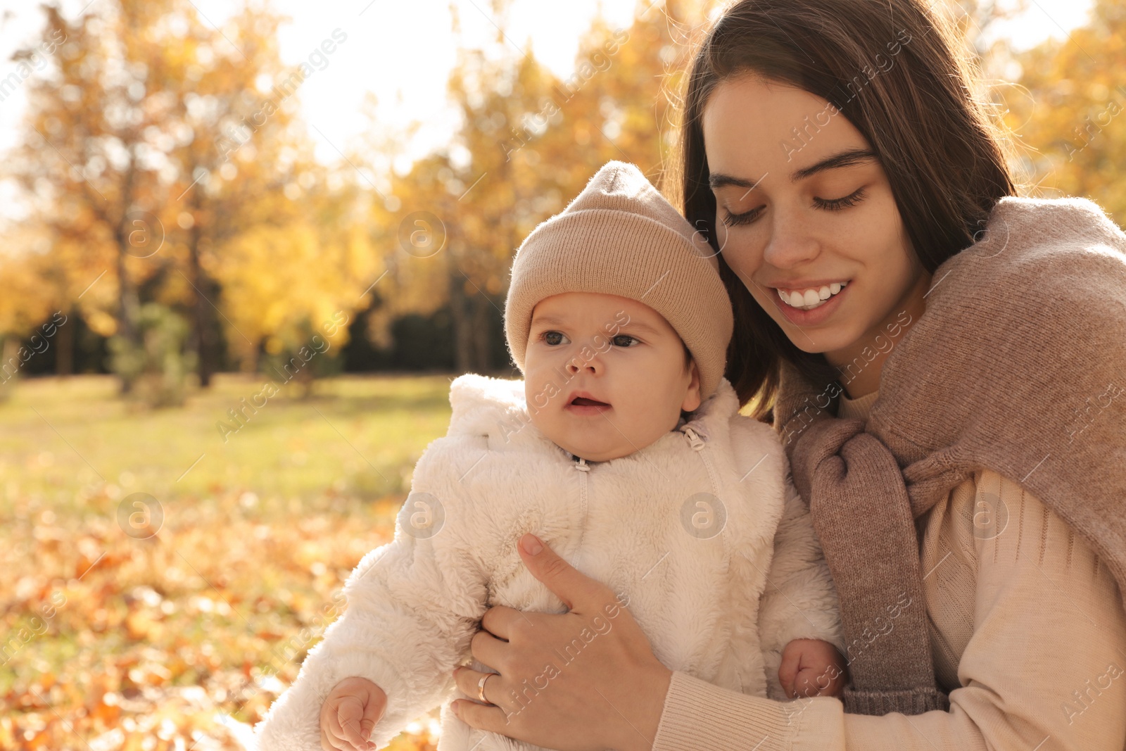 Photo of Happy mother with her baby son in autumn park, space for text