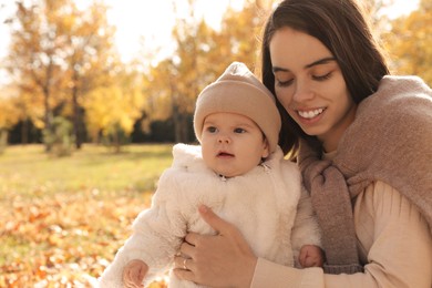 Photo of Happy mother with her baby son in autumn park, space for text