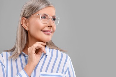 Photo of Portrait of beautiful middle aged woman in eyeglasses on light grey background, space for text