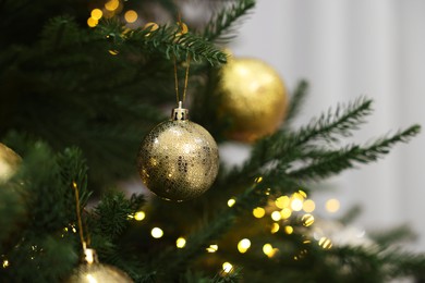 Photo of Christmas balls hanging on fir tree indoors, closeup. Space for text