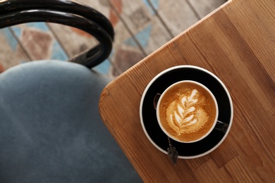 Photo of Cup of fresh aromatic coffee on wooden table, top view