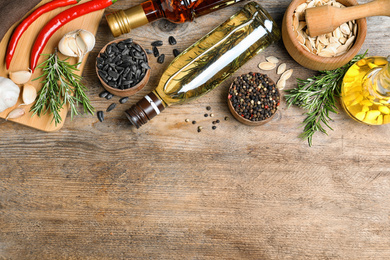 Different cooking oils on wooden table, flat lay. Space for text