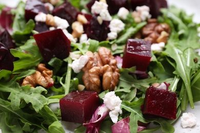 Delicious beet salad with arugula and walnuts on plate, closeup view