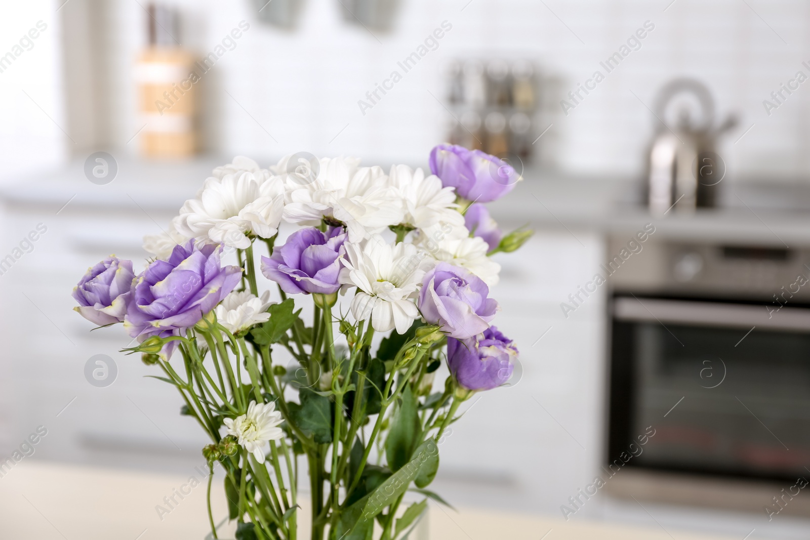 Photo of Vase with beautiful flowers in kitchen interior