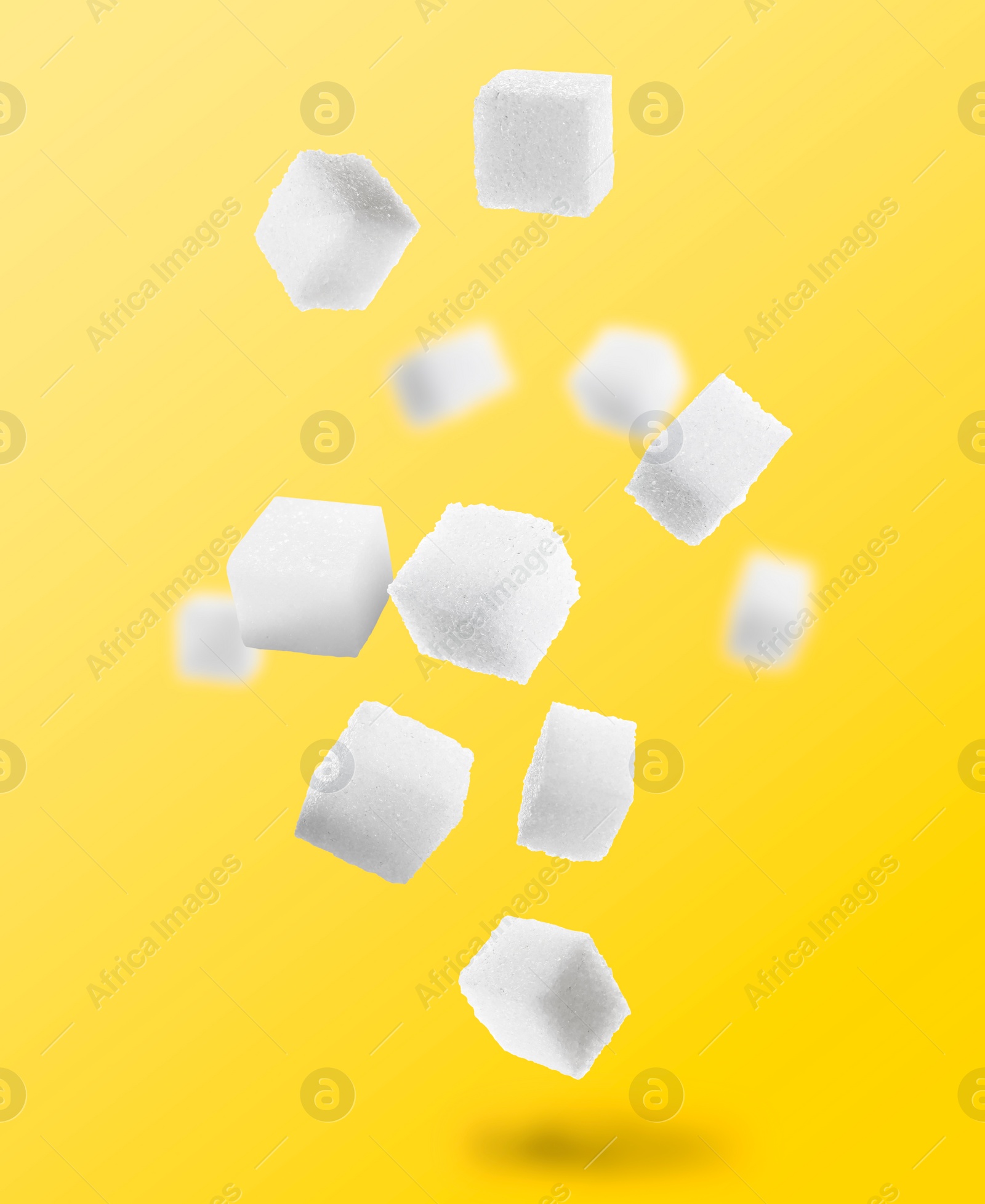 Image of Refined sugar cubes in air on yellow background