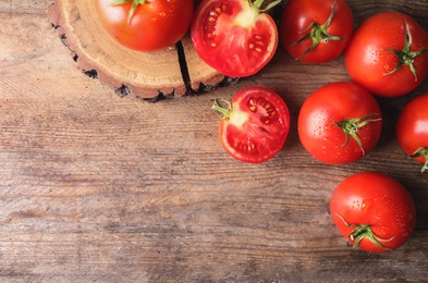 Photo of Fresh ripe tomatoes on wooden table, flat lay. Space for text