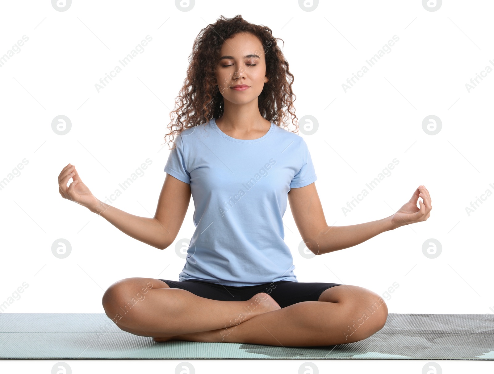 Photo of Beautiful African-American woman meditating on yoga mat against white background