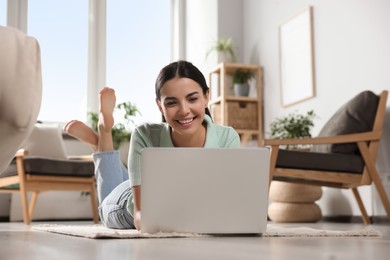 Photo of Young woman working with laptop on floor at home