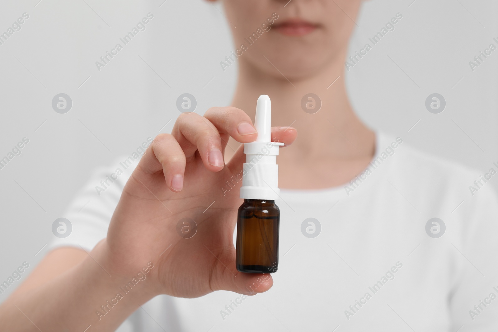 Photo of Woman holding nasal spray on white background, closeup