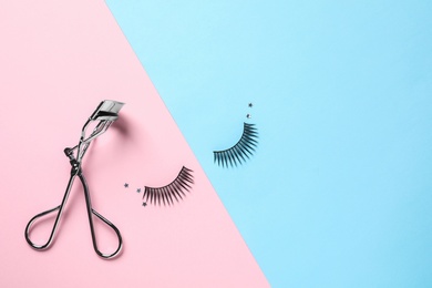 Photo of False eyelashes and curler on color background, flat lay. Space for text