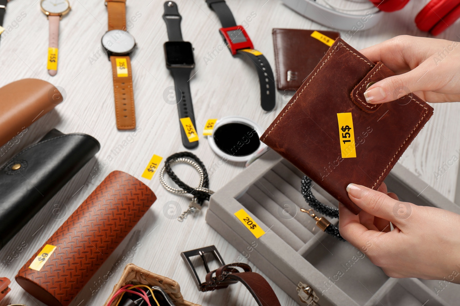 Photo of Woman holding wallet near table with different stuff, closeup. Garage sale