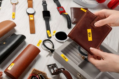 Photo of Woman holding wallet near table with different stuff, closeup. Garage sale