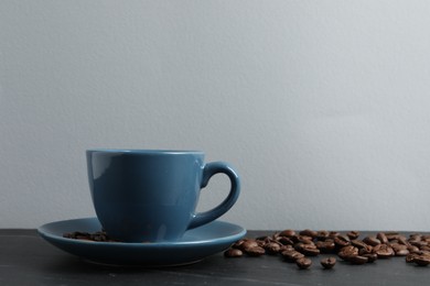 Photo of Cup of aromatic coffee and beans on grey table. Space for text