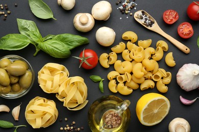Photo of Different types of pasta, spices and products on black background, flat lay