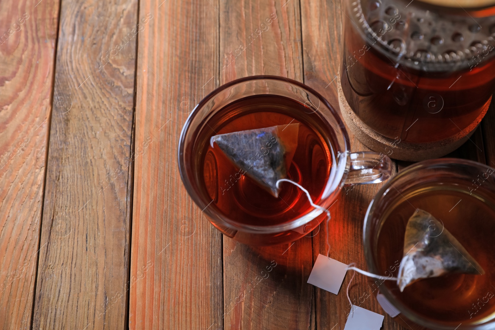 Photo of Tea bags in cups on wooden table, above view. Space for text