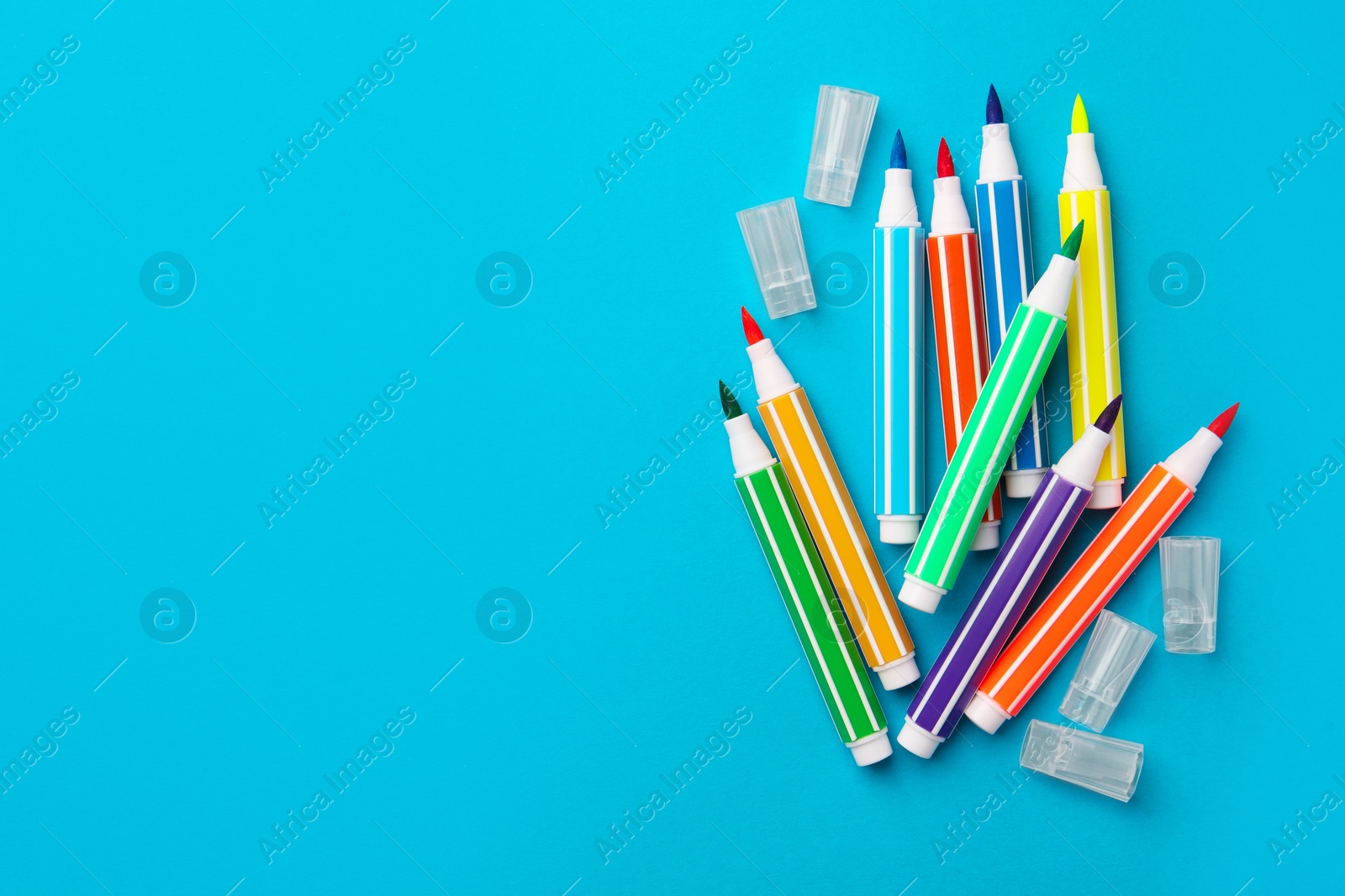 Photo of Many bright markers on light blue background, flat lay. Space for text