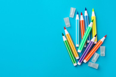 Many bright markers on light blue background, flat lay. Space for text