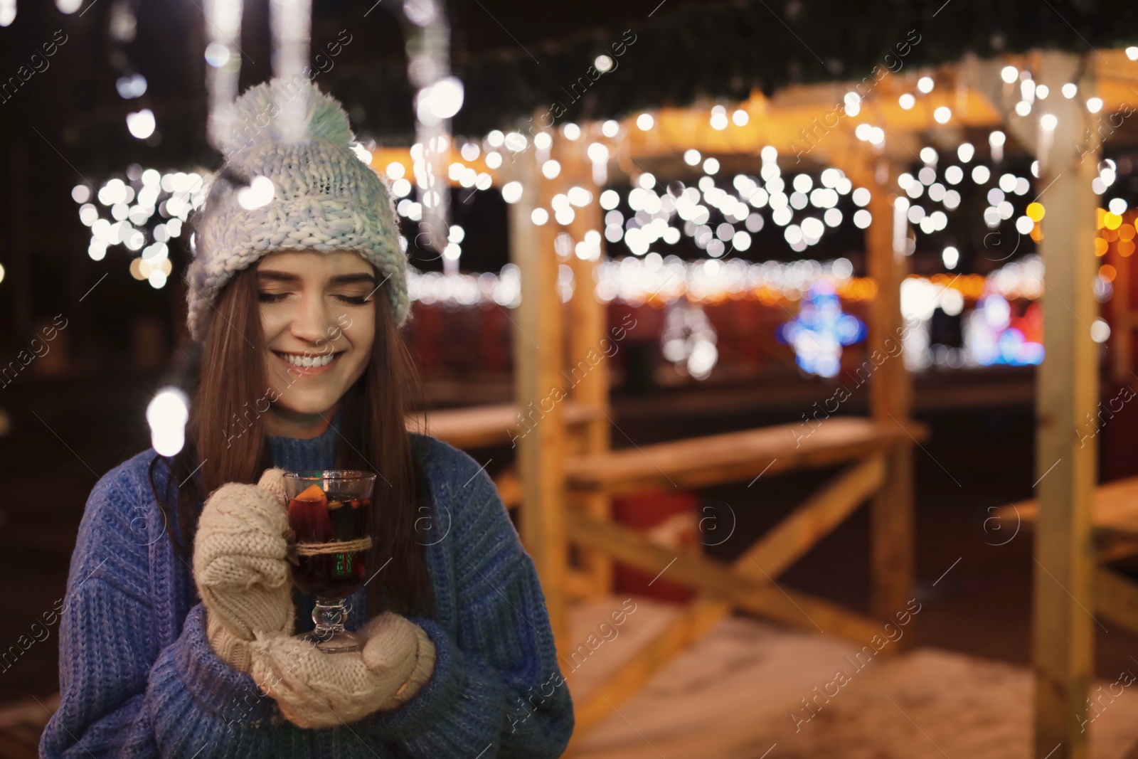 Photo of Woman with glass cup of mulled wine at winter fair. Space for text