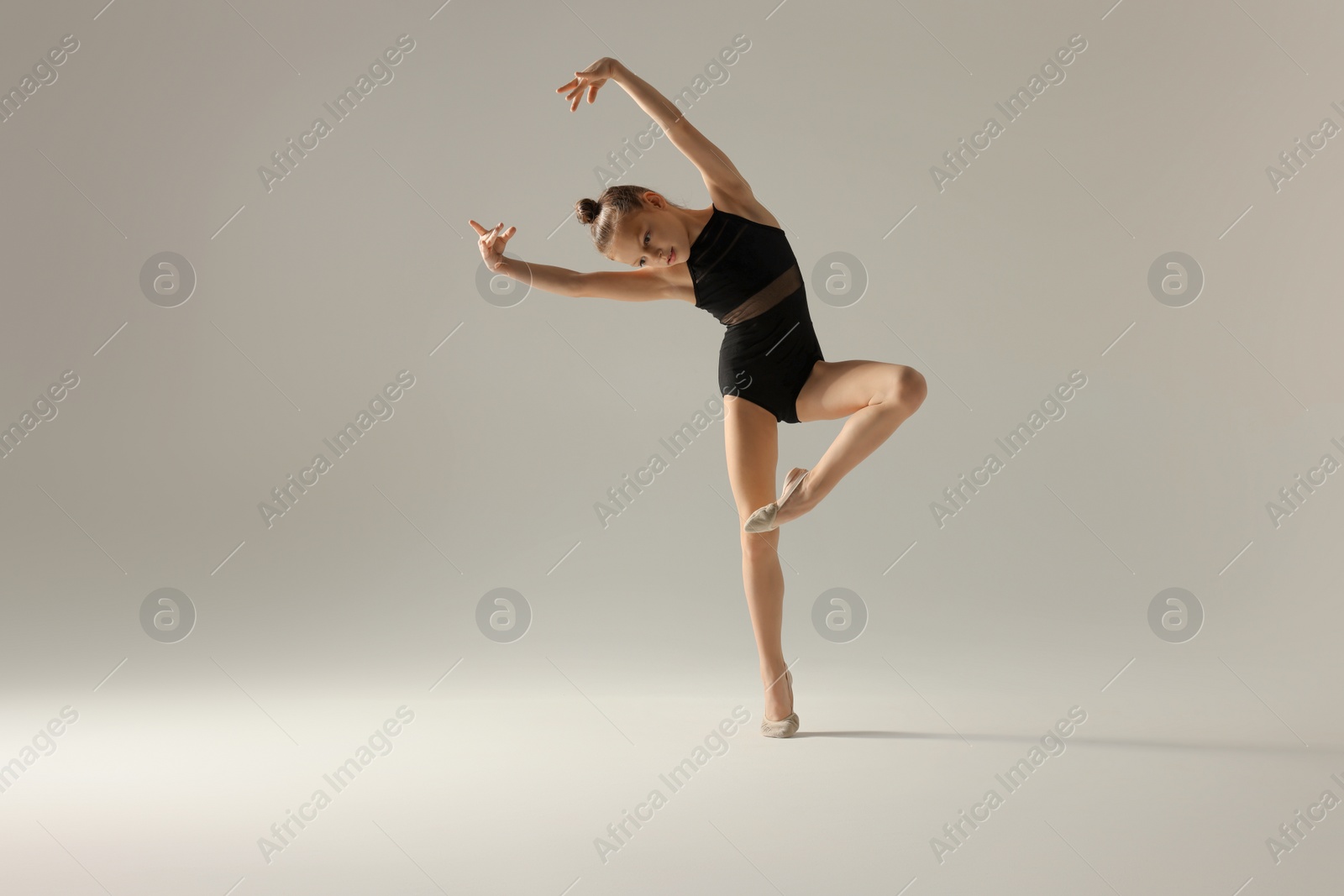 Photo of Cute little girl doing gymnastic exercise on white background