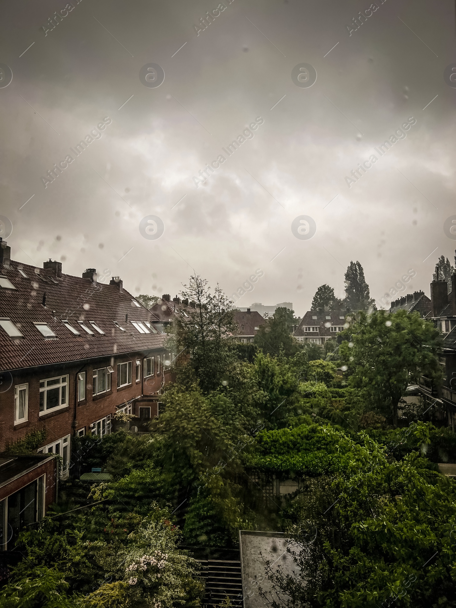 Photo of Beautiful cityscape with residential buildings on rainy day, view from window