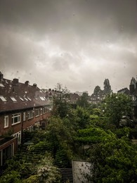 Beautiful cityscape with residential buildings on rainy day, view from window