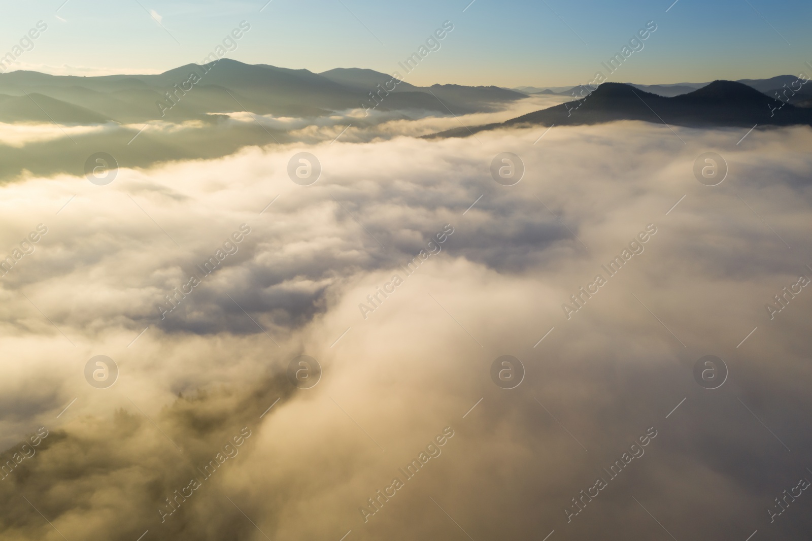 Image of Aerial view of beautiful mountains covered with fluffy clouds on sunny day. Drone photography