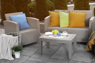 Beautiful rattan garden furniture, soft pillows and different decor elements outdoors