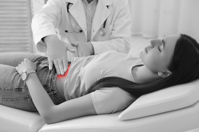 Image of Gastroenterologist examining patient with abdominal pain on couch in clinic, closeup. Black and white effect with red accent