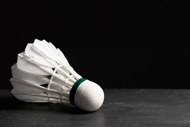 Feather badminton shuttlecock on grey table against black background, closeup. Space for text