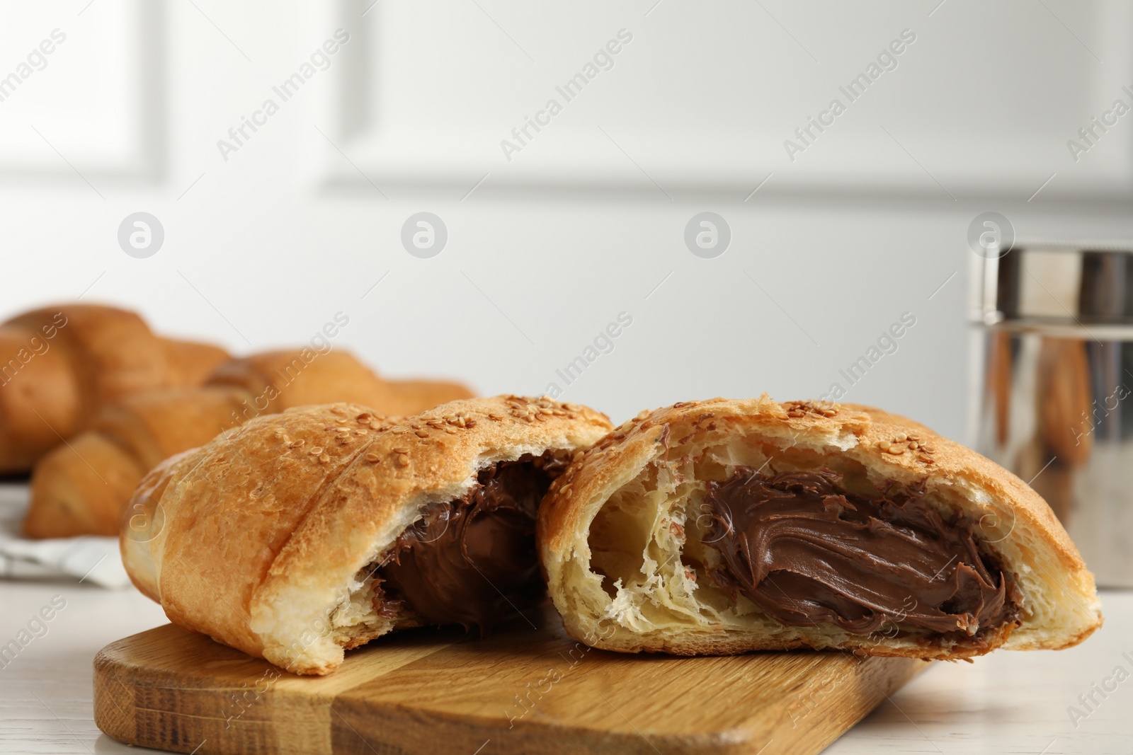 Photo of Tasty croissant with chocolate and sesame seeds on wooden board. Space for text