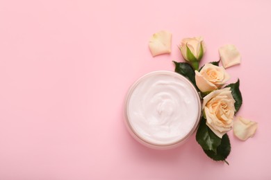 Jar of body cream with rose flowers on light pink background, flat lay. Space for text