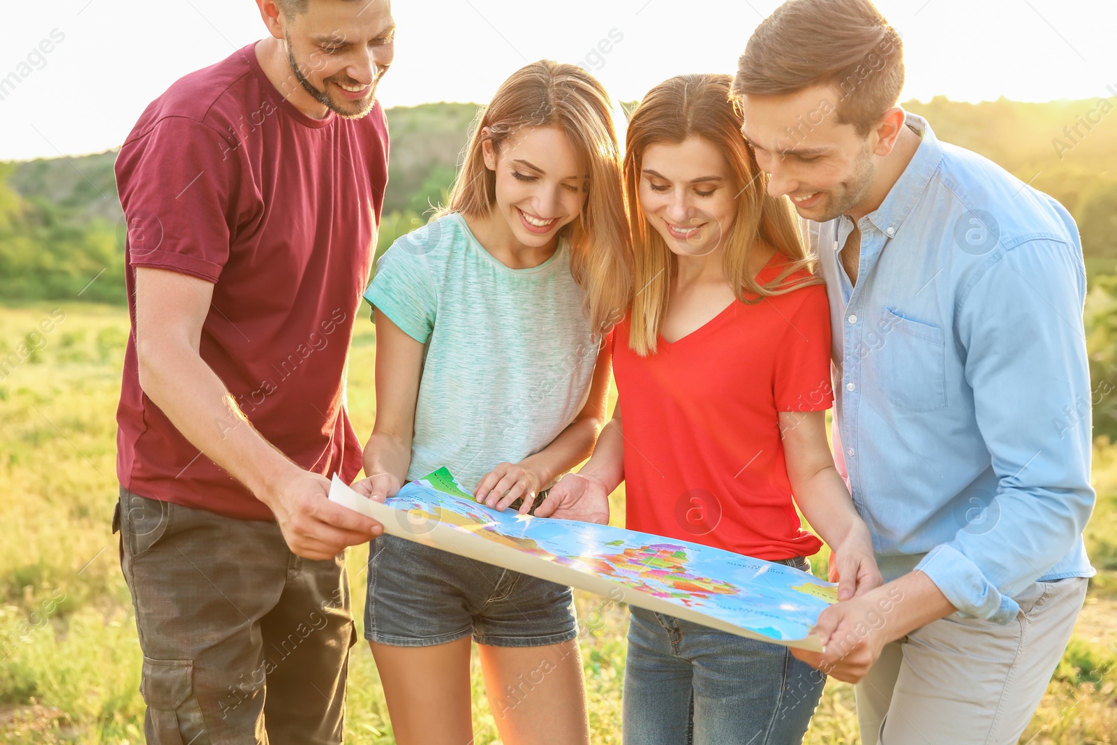 Photo of Group of young people exploring map outdoors. Camping season