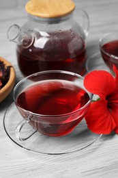 Photo of Delicious hibiscus tea and beautiful flower on light wooden table