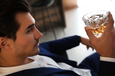 Young man with glass of whiskey indoors