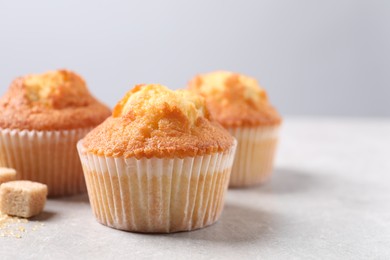 Delicious sweet muffins and brown sugar on light grey textured table, closeup. Space for text