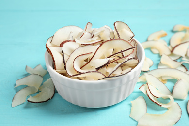 Photo of Tasty coconut chips on light blue wooden table