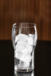 Photo of Glass with ice cubes on table against blurred background