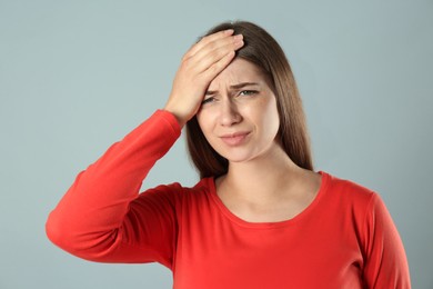 Photo of Young woman suffering from migraine on grey background