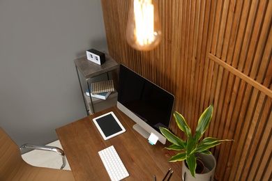 Photo of Stylish workplace with modern computer near wooden wall. Space for text