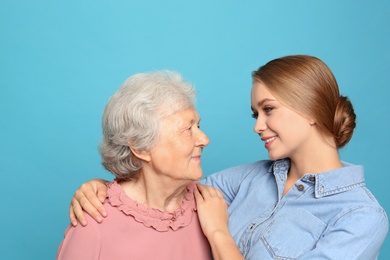 Photo of Young woman and her grandmother on light blue background