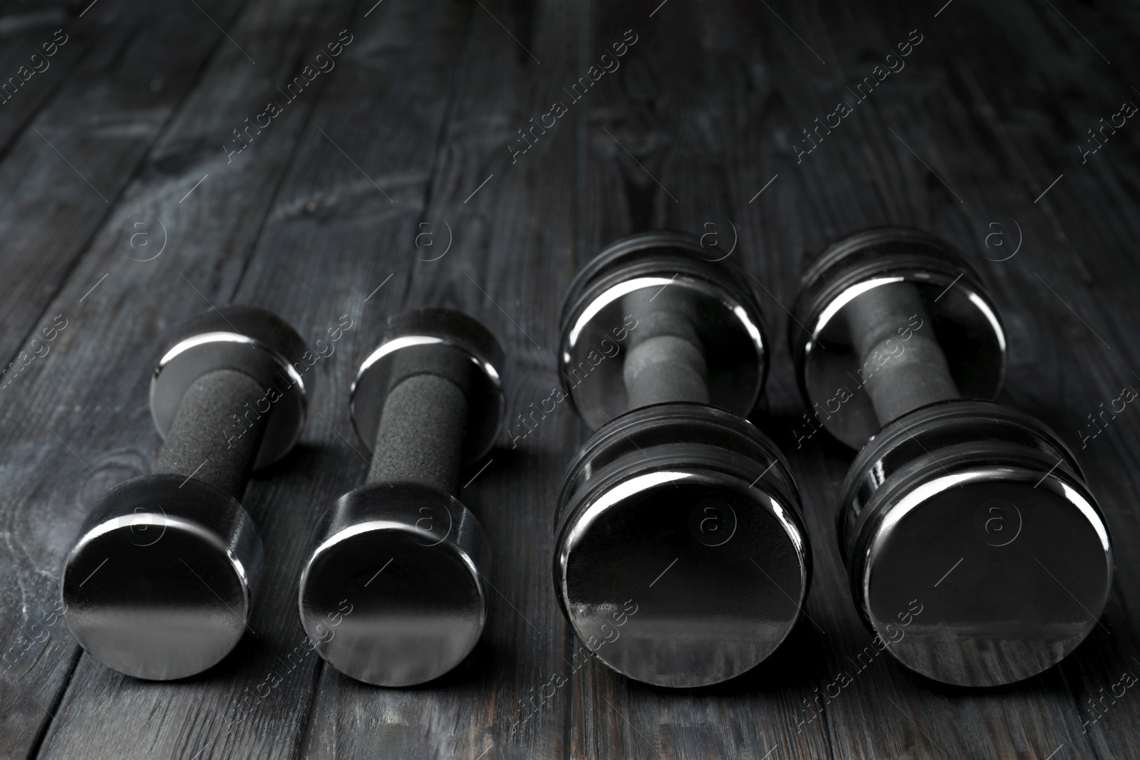 Photo of Set of metal dumbbells on black wooden table