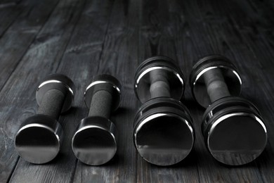 Set of metal dumbbells on black wooden table