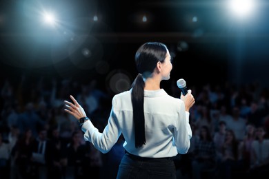 Image of Motivational speaker with microphone performing on stage, back view