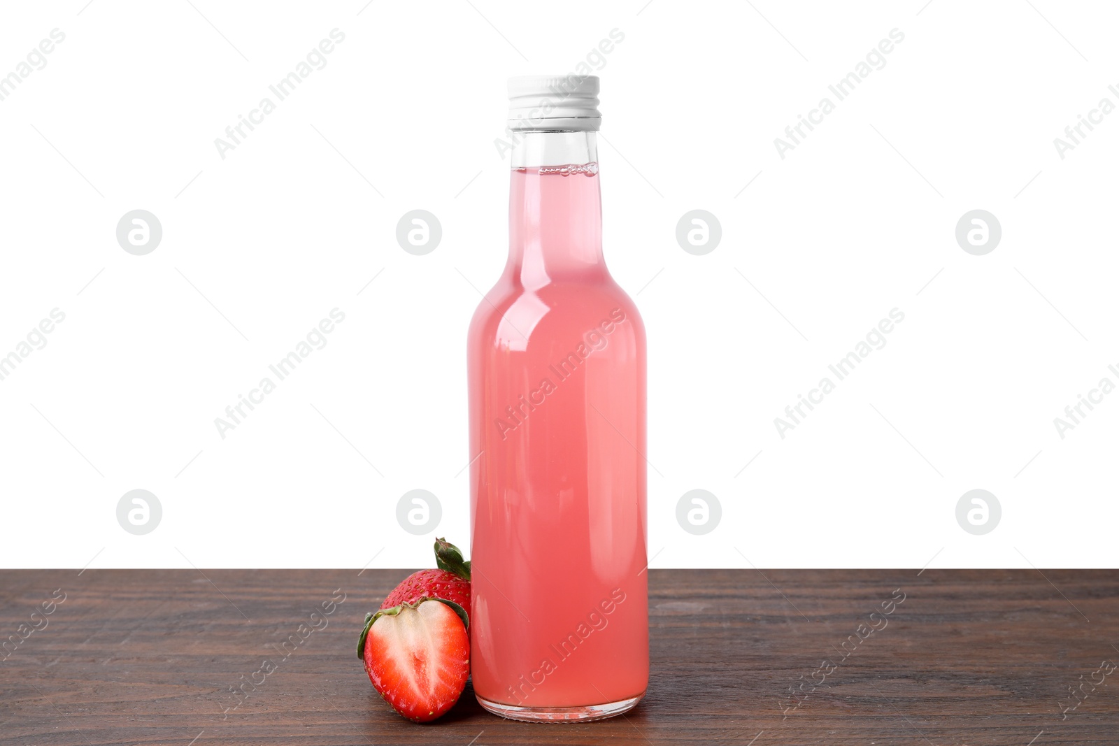 Photo of Delicious kombucha in glass bottle and strawberries on wooden table against white background