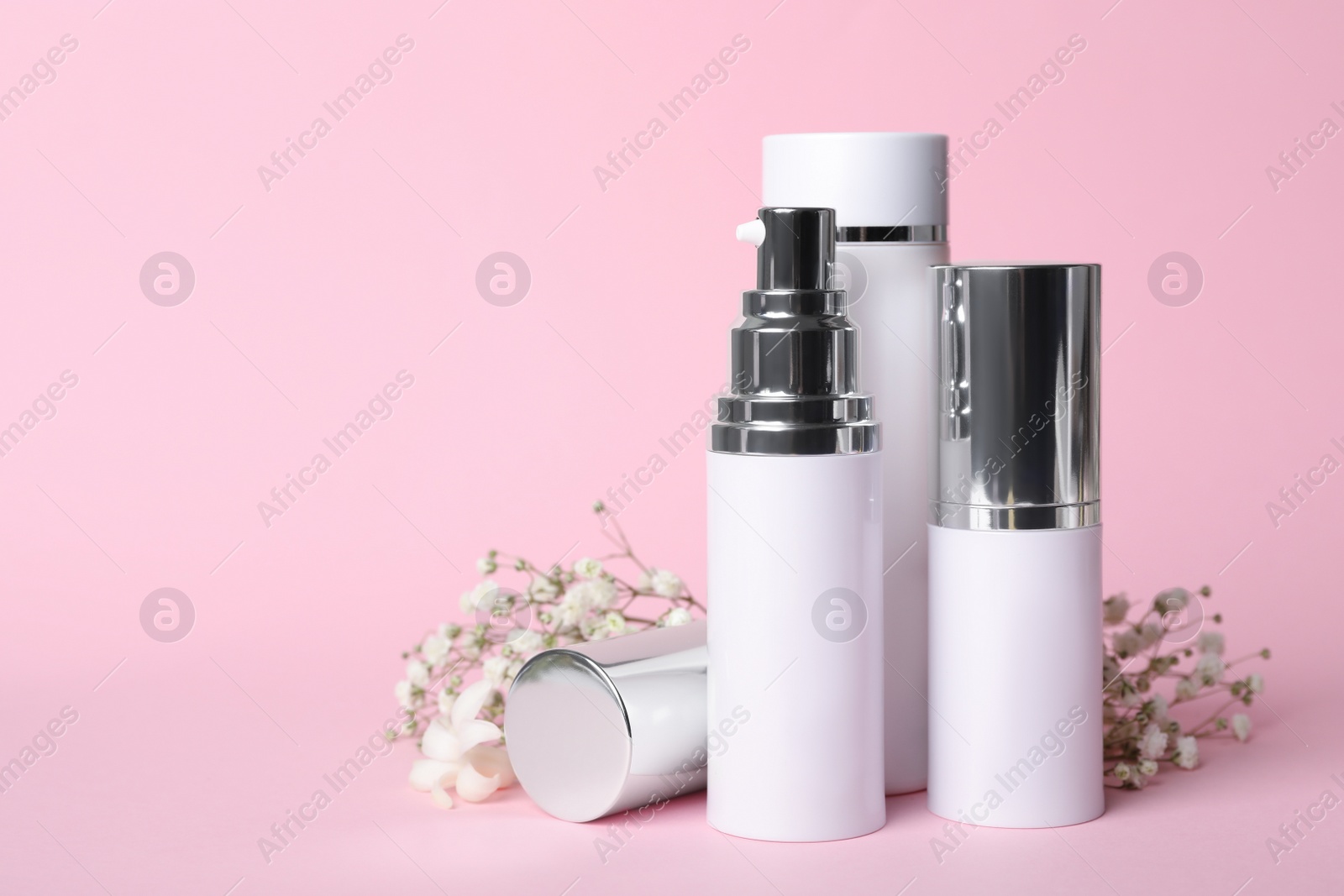 Photo of Set of luxury cosmetic products and flowers on pink background. Space for text