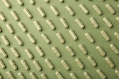 Vitamin capsules on olive background, flat lay