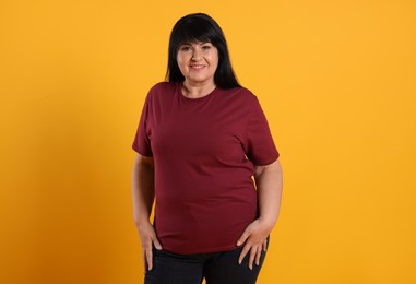 Photo of Beautiful overweight mature woman with charming smile on yellow background
